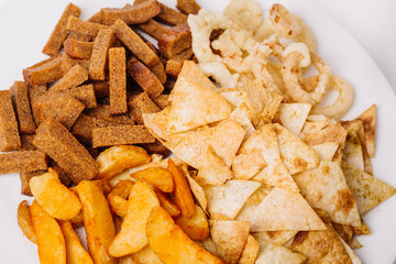 Fast food snacks composition with onion rings,  crackers, baked potatoes, chips, toast.