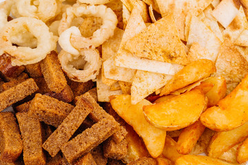 Fast food snacks composition with onion rings,  crackers, baked potatoes, chips, toast.
