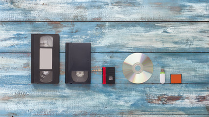 Video cassettes, audio cassettes, and USB, flash drive on the old vintage blue background. The...