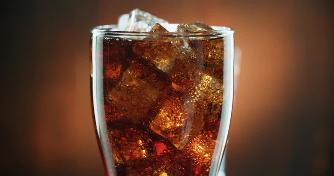 Cola with ice. close-up for a very large glass of cold coke with ice cubes rotation