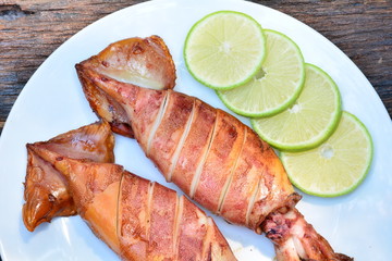Grilled squid with lemon on white plate on wood table,sea food of Thailand