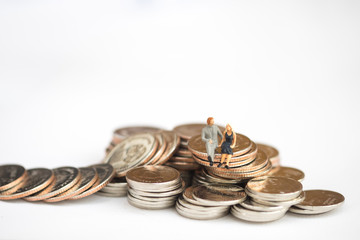 Miniature people: Small couple figures in love sitting on stack of coin in front of house. Money, Love and Valentine's day concepts.