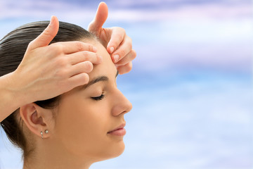 Hands relieving emotional tension on woman's forehead.