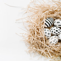 Fancy Easter eggs in nest on white background. Flat lay, top view. Traditional spring concept.