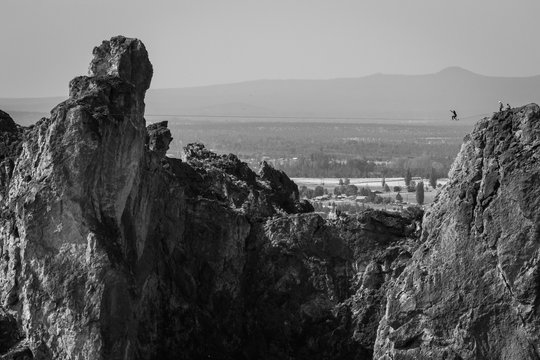 Person tight rope walking across cliff peaks, black and white 