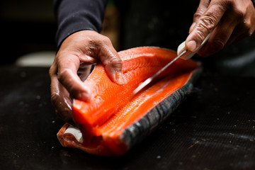 Hands of a male filleting salmon 