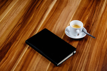 Notizbuch und Kaffeetasse auf Holztisch