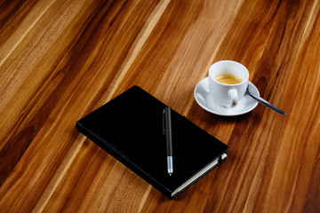 Notizbuch und Kaffeetasse auf Holztisch