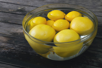 A bunch of lemon and grapefruit in a bowl full of water. Selective focus and small depth of field.