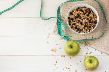 Healthy breakfast. Fitness. Bowl of muesli, bilberry and apples on white wooden background.