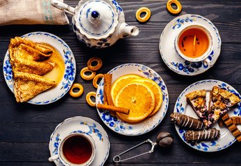 Tea with a nice treat of pancakes, orange, Chocolate and pie