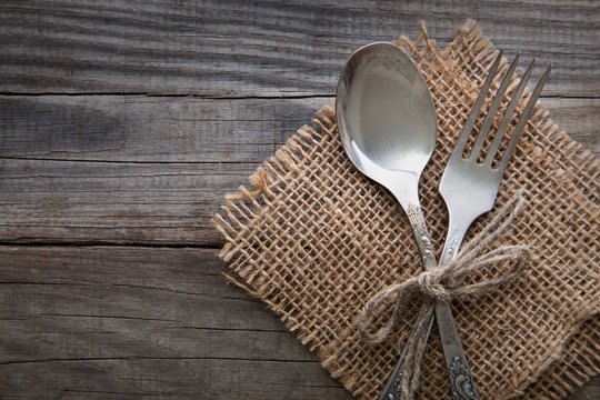 Old fork and spoon on a wooden table napkin and burlap, grunge rustic style, top view.