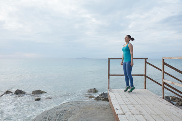 Young woman standing on wooden bridge by the sea