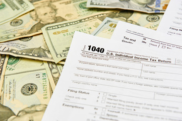 1040 Individual Tax Return form on top of a table full of paper money.