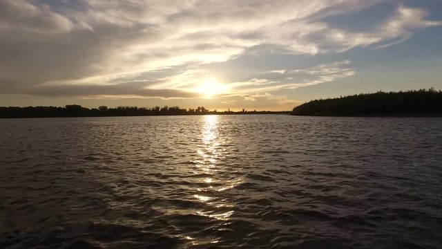 Scenic landscape. View on a riverbank from a boat riding on the river Volga at sunset. 4K