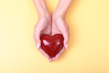 Fototapeta premium Female hands giving red heart, isolated on gold background