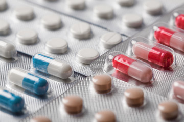 Pile of medical tablets and pills in silver plastic boxes