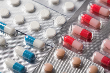 Pile of medical tablets and pills in silver plastic boxes