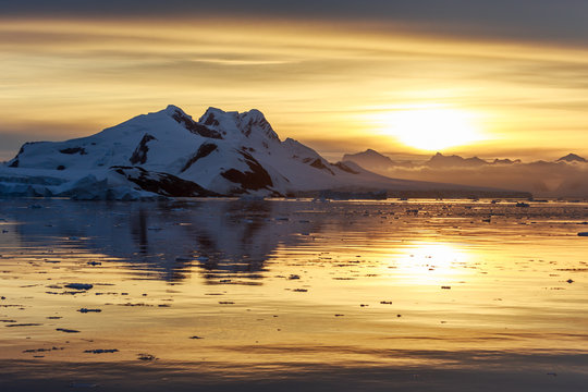 Sunset over the mountains and drifting icebergs at Lemaire Strait, Antarctica
