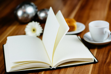Notizbuch, Croissant und Kaffeetasse auf Holztisch