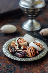 Pecan nuts on metal plate over black rustic surface.