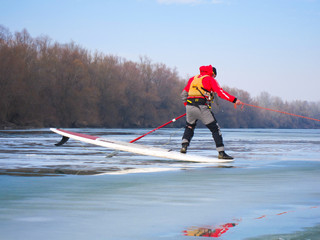 Man standing on SUP. Rescue work on frozen river ice. Winter kayaking on the river Danube.