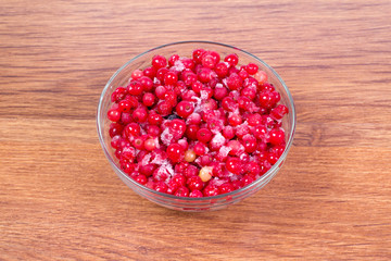 Plate frozen red currants on a wooden background. Harvesting of berries for the winter.