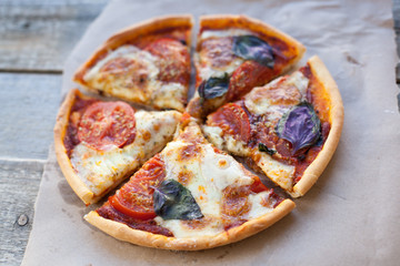 Appetizing pizza margarita on a wooden table in daylight. Vegetarian dish. Top view