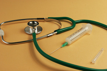 Stethoscope and syringe on orange background.