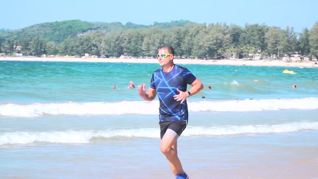 mann l&auml;uft mit laufschuhen und kurzer hose am strand von bang tao, phuket, thailand