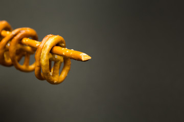 Background texture of salted salty pretzels and mini sticks in the traditional form of the hinge assembly on a black background. Space for text.