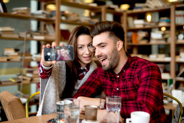 Couple at cafe bar making selfie with smart phone. Friendship concept together doing stuffs.