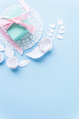 a gift on a white napkin and white paper flowers on blue background