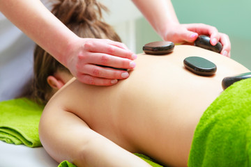 Massage with hot rocks stones in beautician