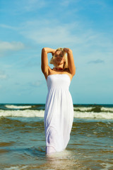 Fototapeta na wymiar Blonde woman wearing dress walking in water