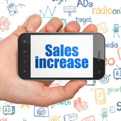 Marketing concept: Hand Holding Smartphone with Sales Increase on display