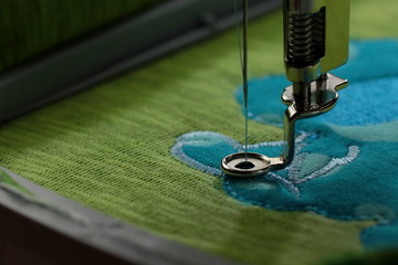 Embroidery with embroidery machine - comic dog application - stitiching details - background and foreground blanked out blurry  © R_boe