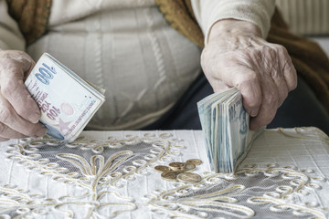 Wrinkled hands counting Turkish Lira banknotes