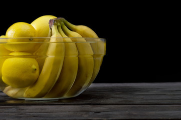 A bunch of fresh yellow fruit in a bowl full of water. Selective focus and small depth of field.