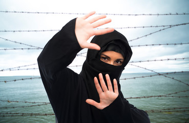 muslim woman in hijab making protective gesture