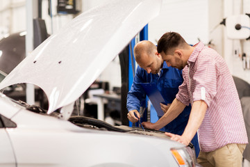 auto mechanic with clipboard and man at car shop