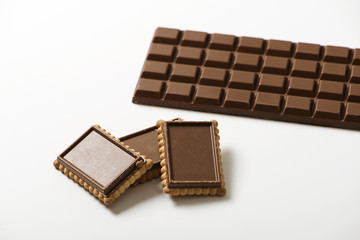 Various chocolate covered cookies next to chocolate tablet on white background. Isolated. Horizontal shoot.