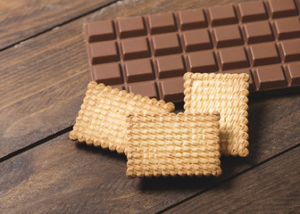 Cookies and chocolate tablet on wooden background. Horizontal shoot.