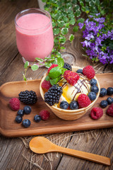 Tasty ice cream dessert with fruit in a waffle bowl.