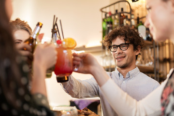 happy friends clinking drinks at bar or cafe