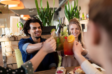 happy friends clinking drinks at restaurant