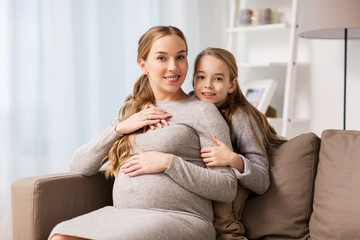 happy pregnant woman and girl hugging at home