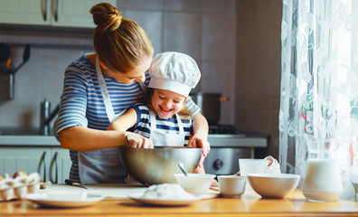 famille heureuse dans la cuisine. mère et enfant préparant la pâte, cuisent des biscuits
