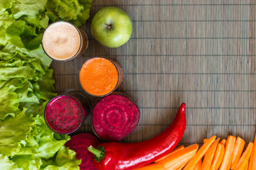 three glasses of different fresh juice. Beet, carrot and apple juices on grey wood background