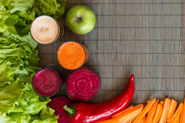 three glasses of different fresh juice. Beet, carrot and apple juices on grey wood background